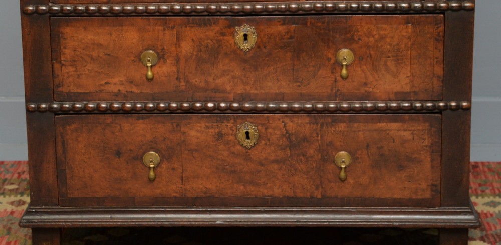 A William and Mary walnut and yew wood chest of four drawers featuring brass teardrop handles and decorative bead moulding. View IV