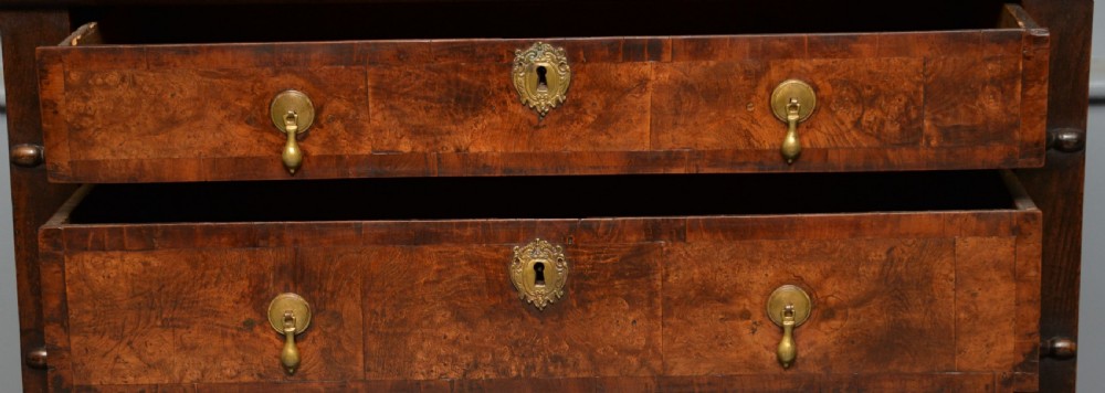 A William and Mary walnut and yew wood chest of four drawers featuring brass teardrop handles and decorative bead moulding. View V