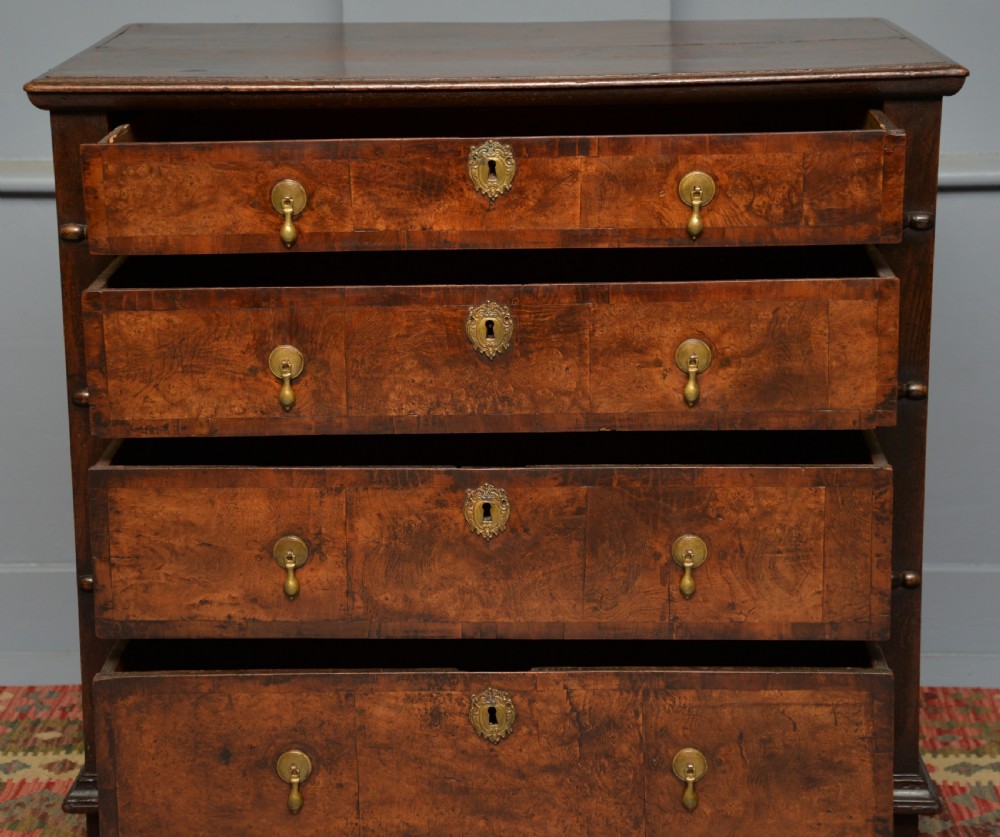 A William and Mary walnut and yew wood chest of four drawers featuring brass teardrop handles and decorative bead moulding. View VI
