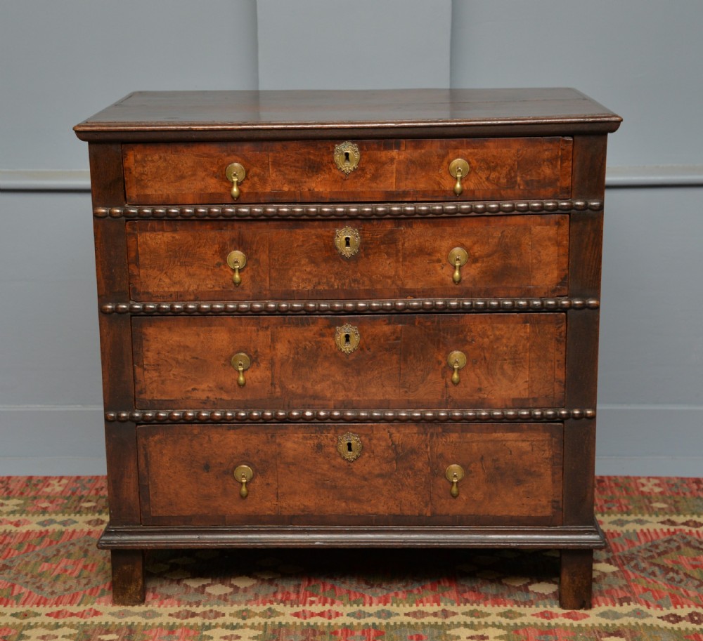 A William and Mary walnut and yew wood chest of four drawers featuring brass teardrop handles and decorative bead moulding. View VII
