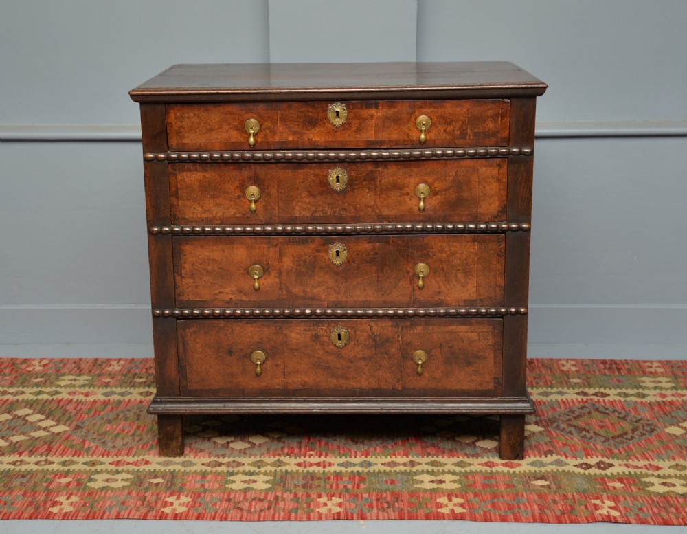A William and Mary walnut and yew wood chest of four drawers featuring brass teardrop handles and decorative bead moulding. View VIII