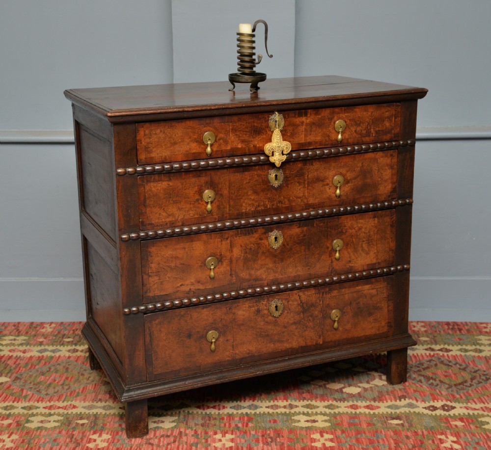 A William and Mary walnut and yew wood chest of four drawers featuring brass teardrop handles and decorative bead moulding. View IX