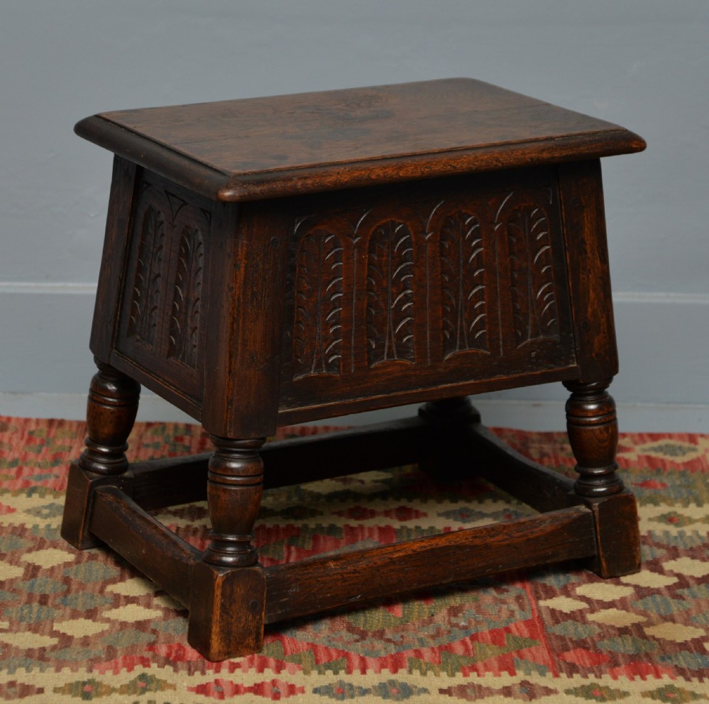 A dark oak box stool featuring carved arched panels, turned baluster legs, and a rectangular top. View VIII