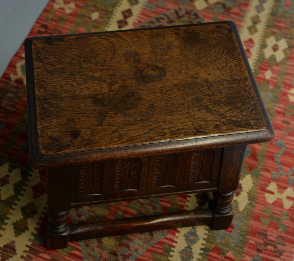 A dark oak box stool featuring carved arched panels, turned baluster legs, and a rectangular top. View XVIII