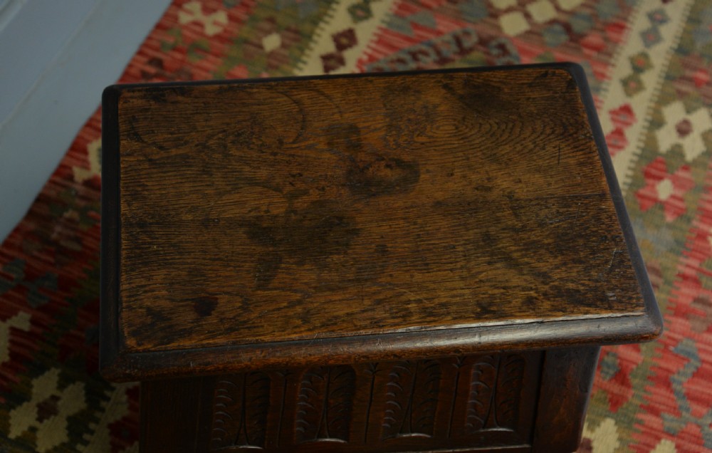 A dark oak box stool featuring carved arched panels, turned baluster legs, and a rectangular top. View XIX