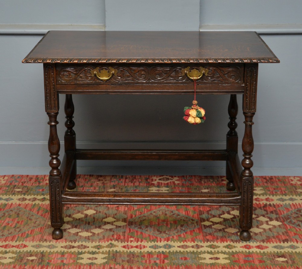 A dark carved oak side table featuring a single scroll-carved frieze drawer, turned legs, and a lower stretcher frame. View V