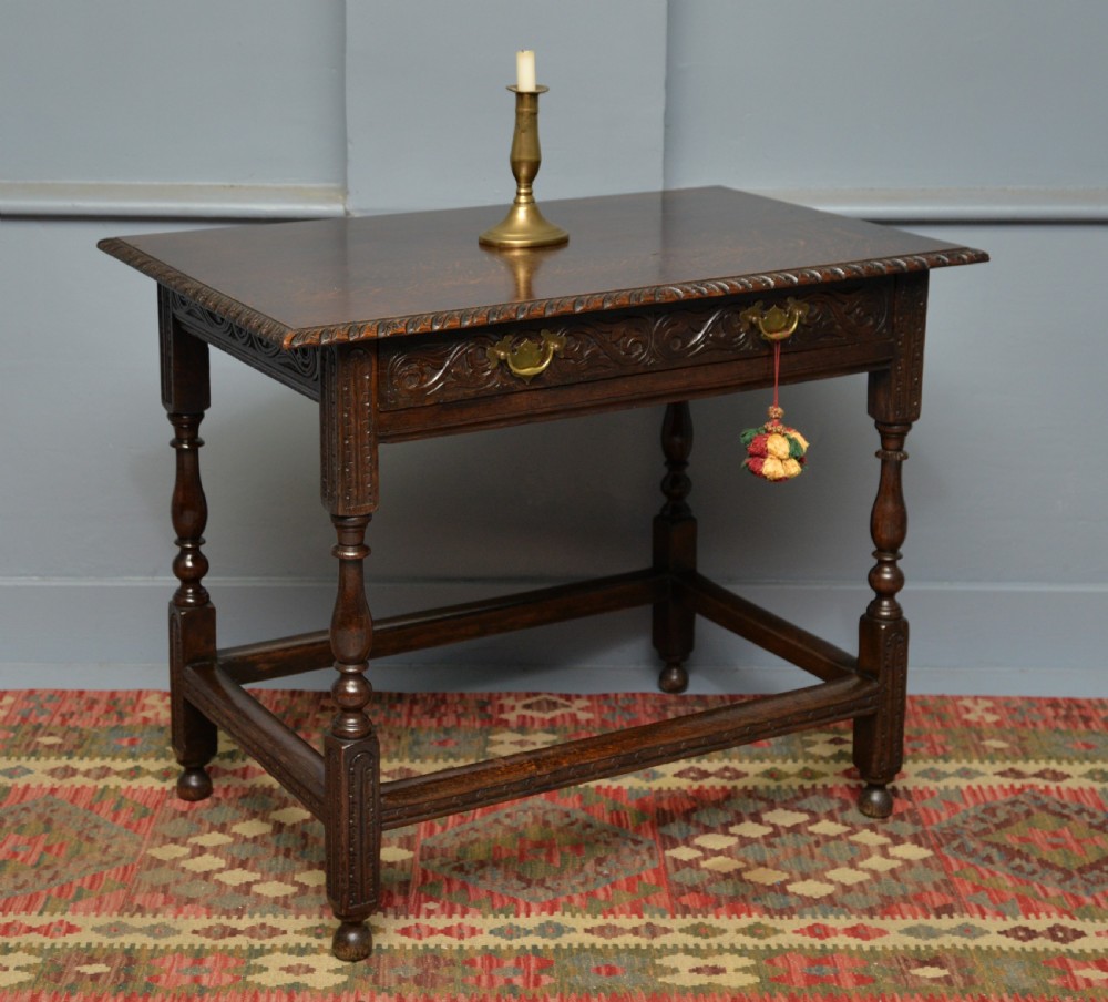 A dark carved oak side table featuring a single scroll-carved frieze drawer, turned legs, and a lower stretcher frame. View VI