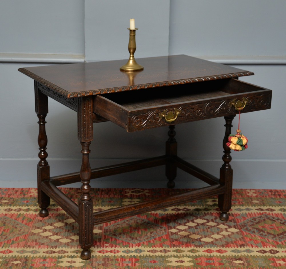 A dark carved oak side table featuring a single scroll-carved frieze drawer, turned legs, and a lower stretcher frame. View IX