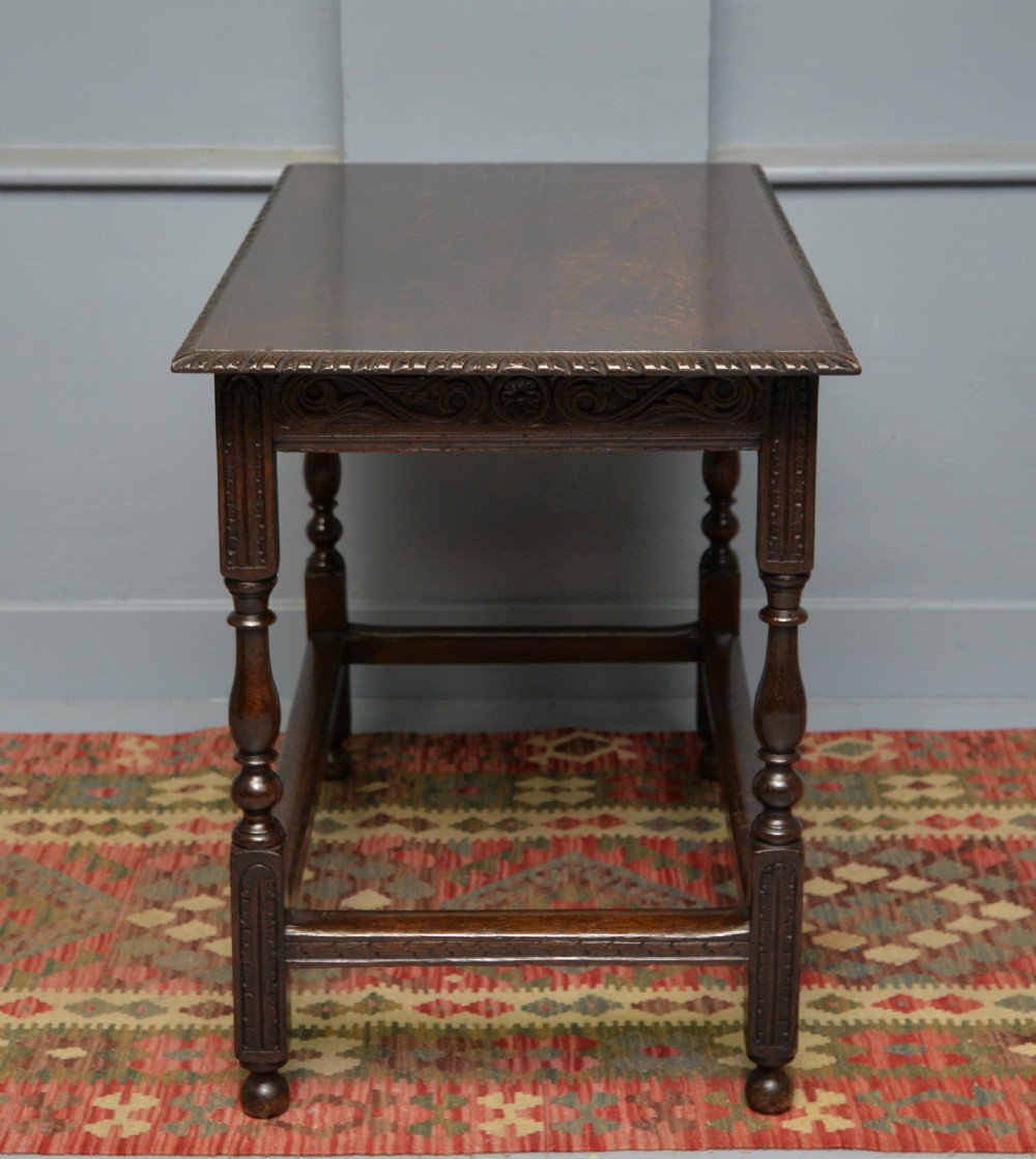 A dark carved oak side table featuring a single scroll-carved frieze drawer, turned legs, and a lower stretcher frame. View XI