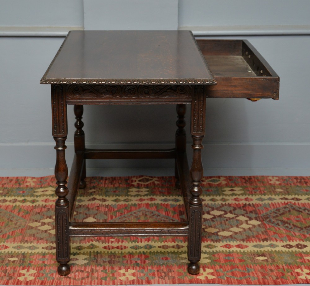 A dark carved oak side table featuring a single scroll-carved frieze drawer, turned legs, and a lower stretcher frame. View XIII