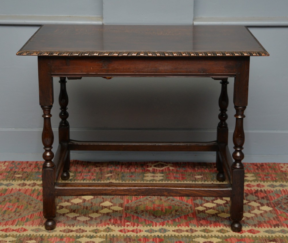 A dark carved oak side table featuring a single scroll-carved frieze drawer, turned legs, and a lower stretcher frame. View XIV