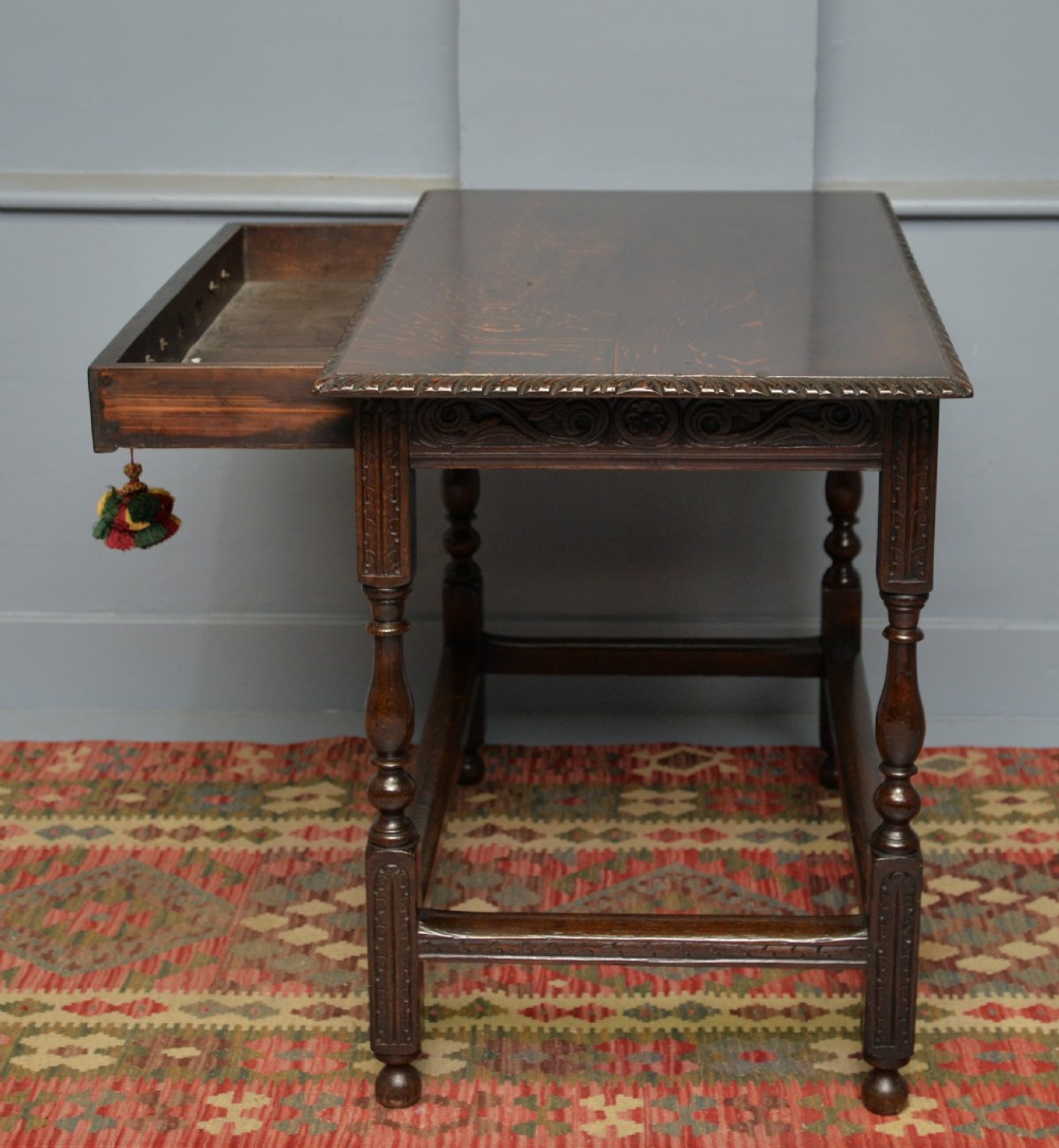 A dark carved oak side table featuring a single scroll-carved frieze drawer, turned legs, and a lower stretcher frame. View XVII