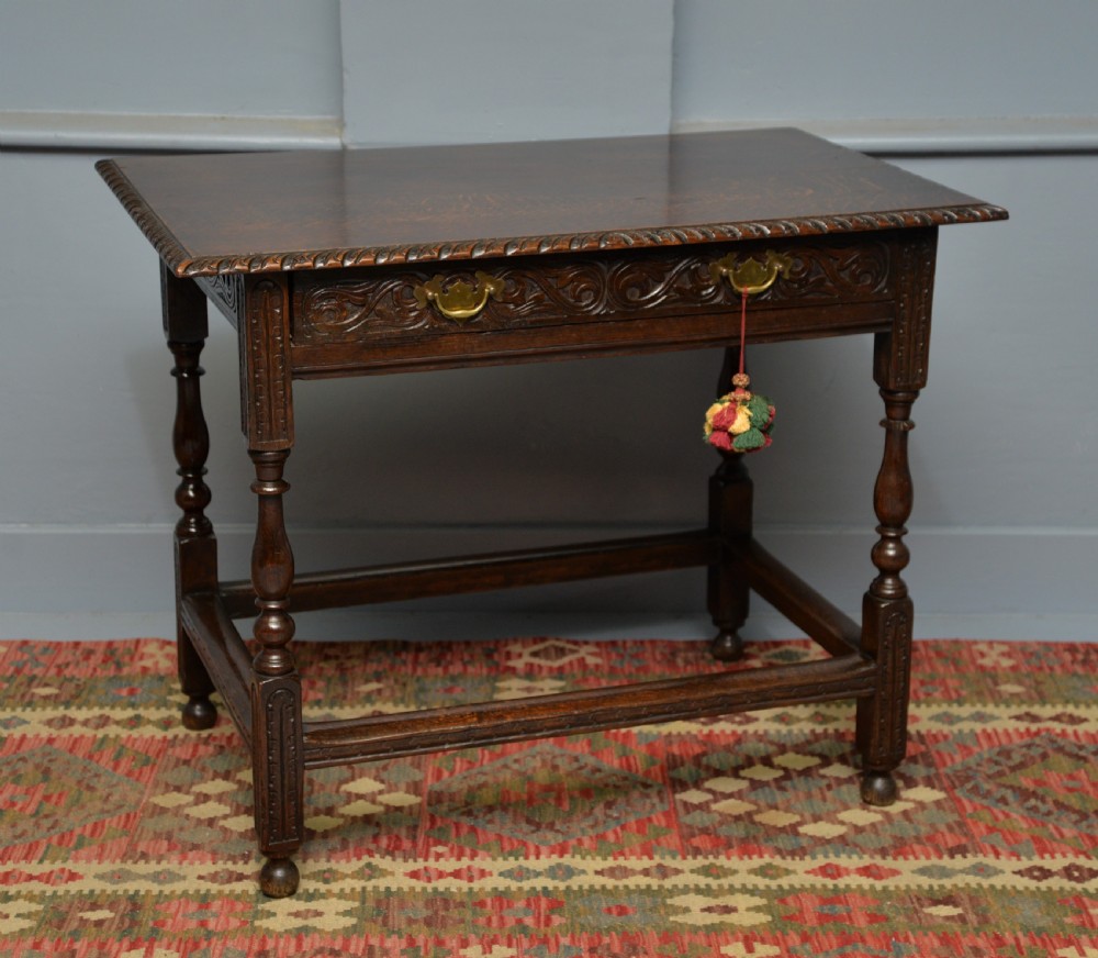 A dark carved oak side table featuring a single scroll-carved frieze drawer, turned legs, and a lower stretcher frame. View XXI