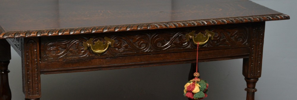 A dark carved oak side table featuring a single scroll-carved frieze drawer, turned legs, and a lower stretcher frame. View XXII
