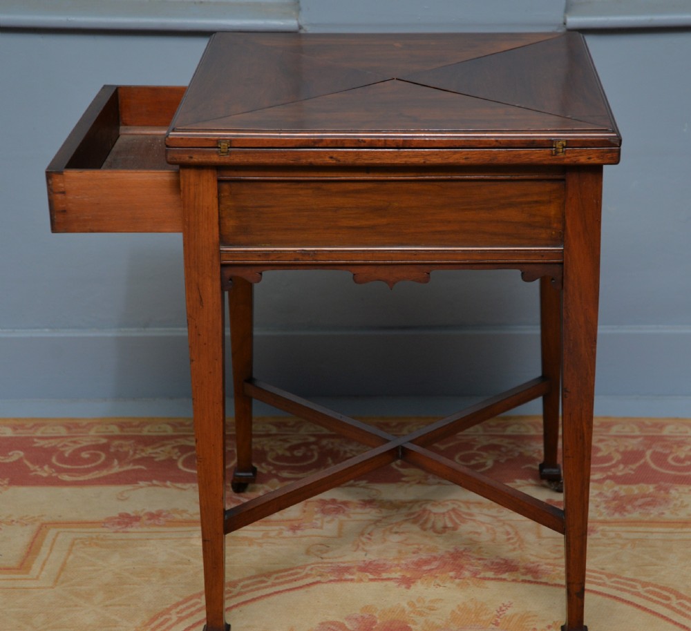 An antique mahogany envelope card table featuring four triangular top flaps, a single drawer with brass drop handles, and tapered legs joined by an X-shaped stretcher. View XIV