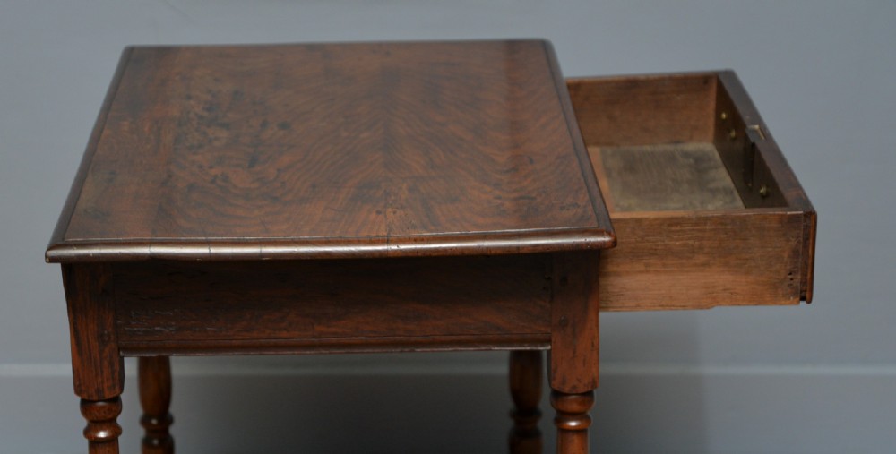 An early 18th-century dark oak side table featuring a rectangular top, single frieze drawer with brass handles, turned legs, and a stretcher base. View VIII
