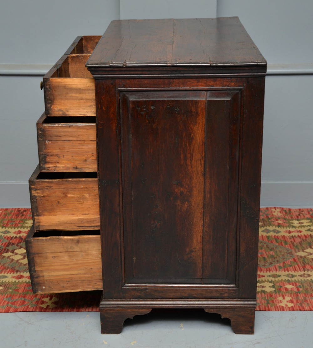An early eighteenth-century Georgian oak chest of drawers featuring a two-over-three drawer configuration, brass escutcheons, turned knobs, and shaped bracket feet. View XII