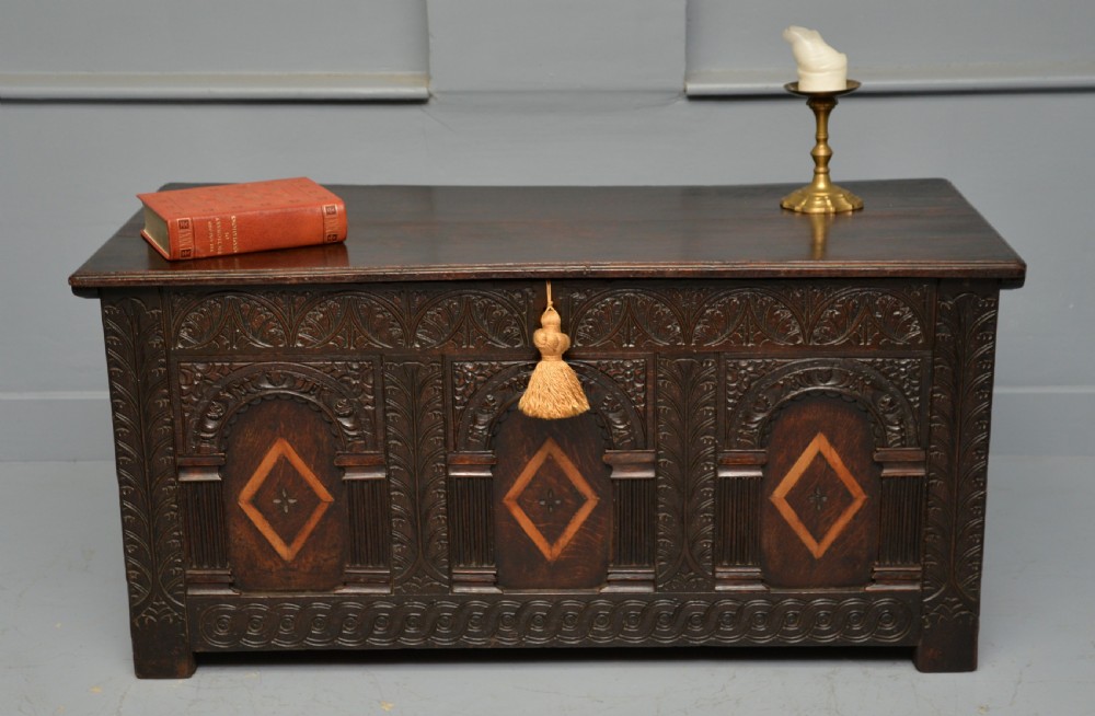 A 17th-century dark oak coffer featuring three carved arcaded front panels with diamond marquetry inlays and detailed frieze carving. View II