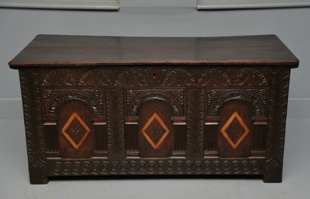 A 17th-century dark oak coffer featuring three carved arcaded front panels with diamond marquetry inlays and detailed frieze carving. View III