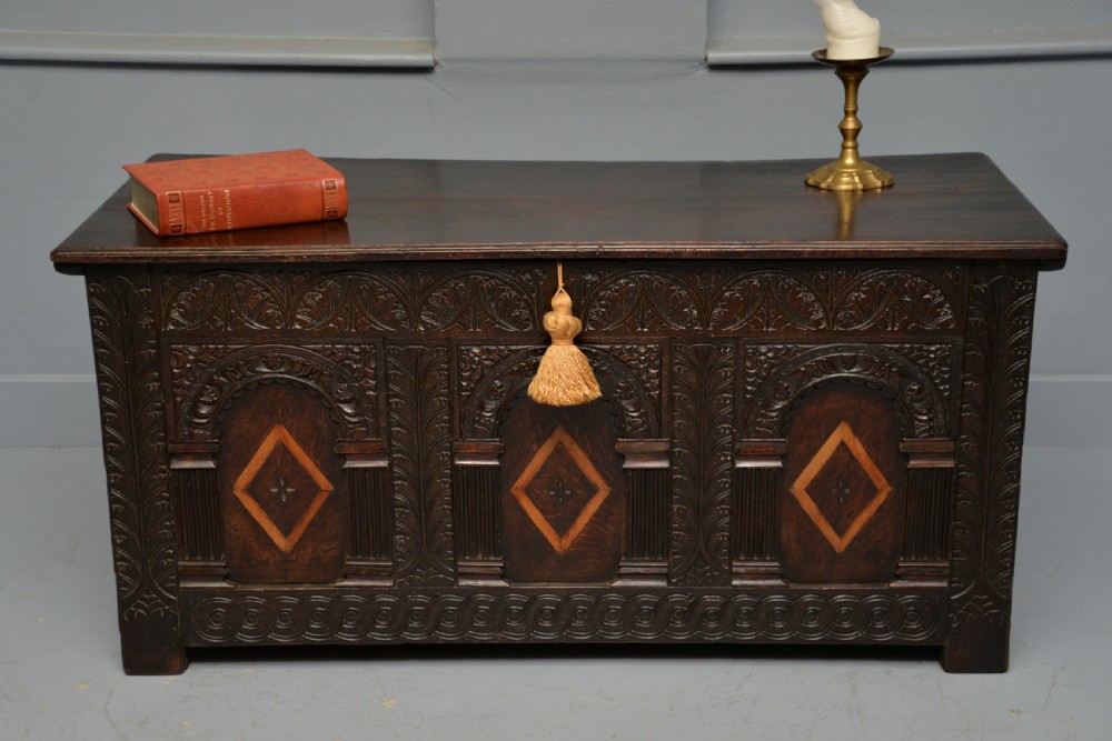 A 17th-century dark oak coffer featuring three carved arcaded front panels with diamond marquetry inlays and detailed frieze carving. View IV