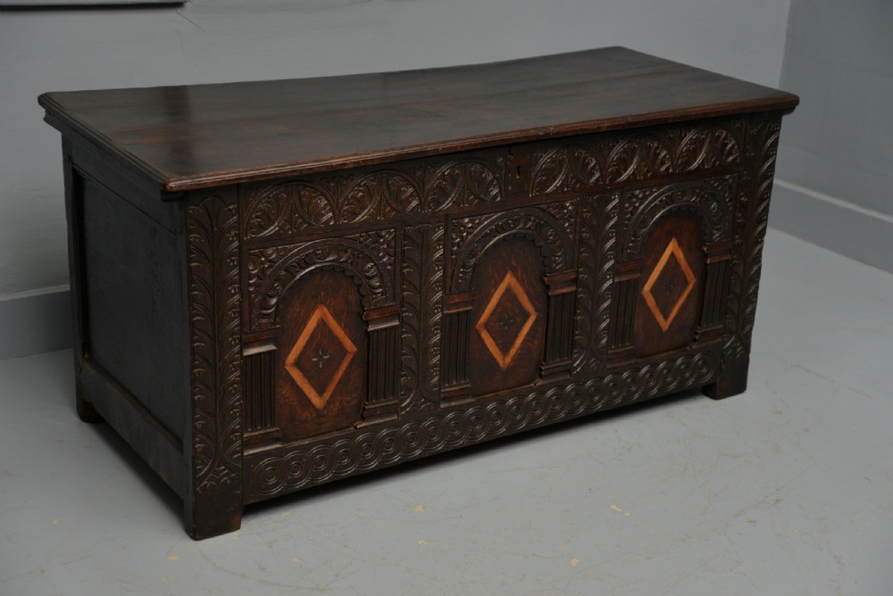 A 17th-century dark oak coffer featuring three carved arcaded front panels with diamond marquetry inlays and detailed frieze carving. View V