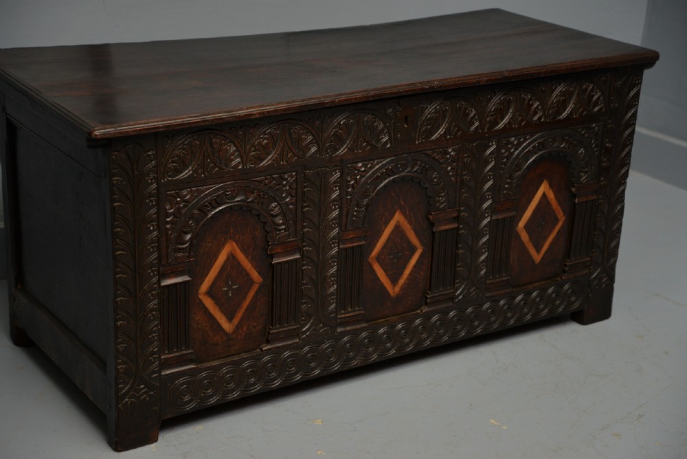 A 17th-century dark oak coffer featuring three carved arcaded front panels with diamond marquetry inlays and detailed frieze carving. View VI