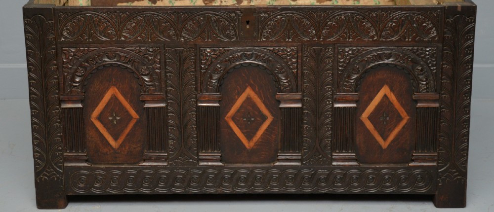 A 17th-century dark oak coffer featuring three carved arcaded front panels with diamond marquetry inlays and detailed frieze carving. View VII