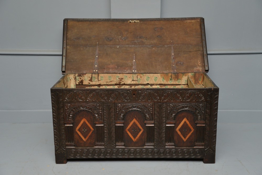 A 17th-century dark oak coffer featuring three carved arcaded front panels with diamond marquetry inlays and detailed frieze carving. View VIII