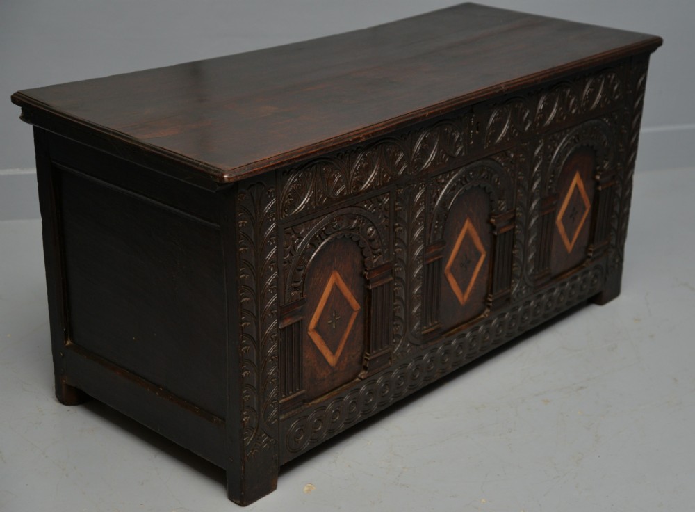 A 17th-century dark oak coffer featuring three carved arcaded front panels with diamond marquetry inlays and detailed frieze carving. View IX