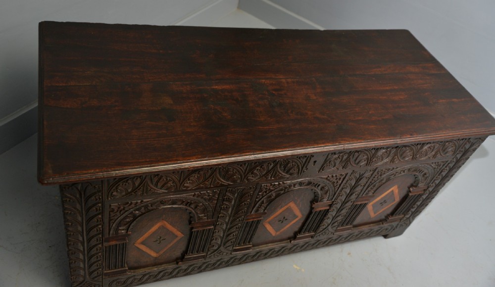 A 17th-century dark oak coffer featuring three carved arcaded front panels with diamond marquetry inlays and detailed frieze carving. View XIII