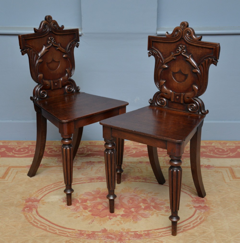 A pair of Regency mahogany hall chairs featuring carved scroll backs with shield motifs and turned reeded front legs. View III