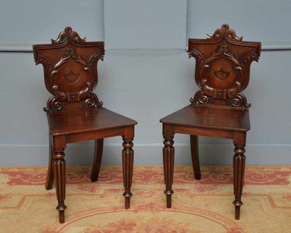 A pair of Regency mahogany hall chairs featuring carved scroll backs with shield motifs and turned reeded front legs. View XIII