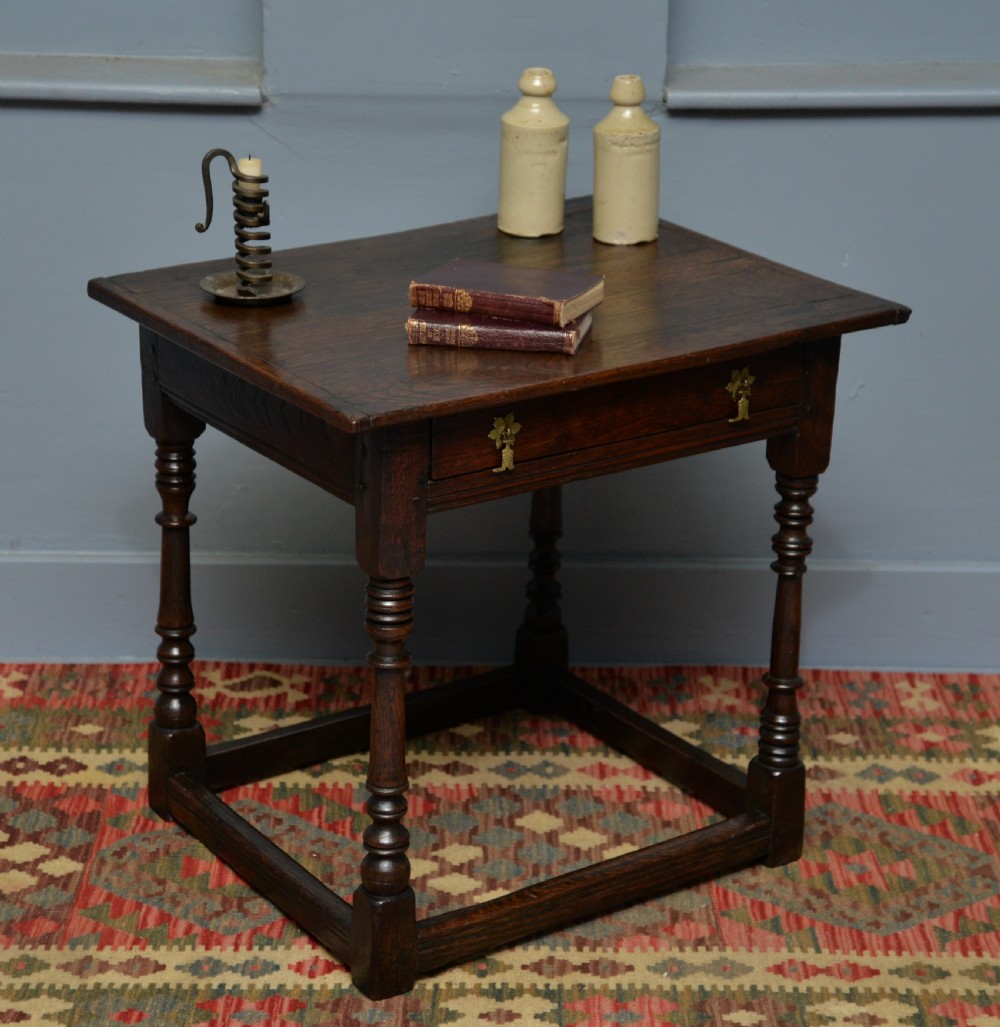 A seventeenth-century dark oak side table with turned legs, a frieze drawer with brass handles, and a low box stretcher. View II