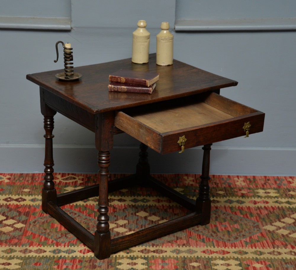 A seventeenth-century dark oak side table with turned legs, a frieze drawer with brass handles, and a low box stretcher. View III