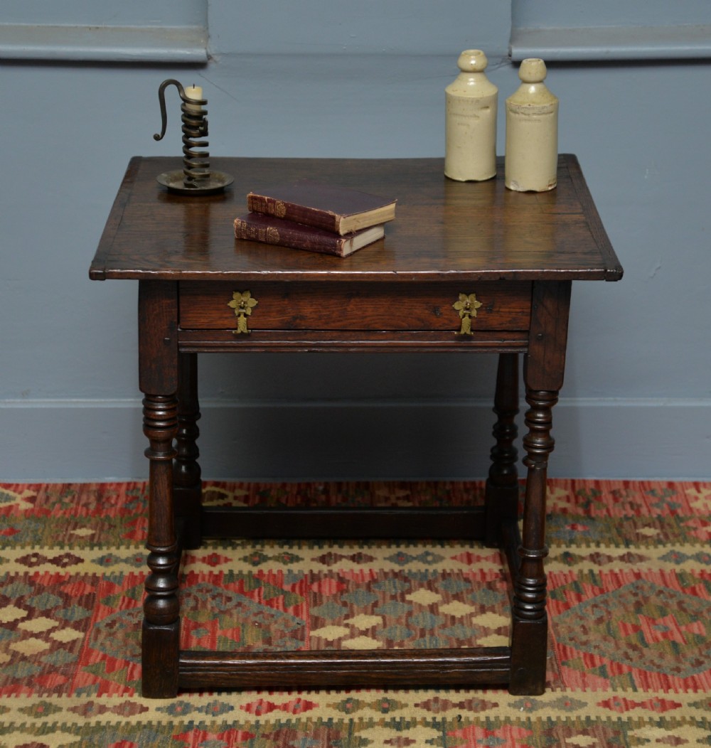 A seventeenth-century dark oak side table with turned legs, a frieze drawer with brass handles, and a low box stretcher. View IV
