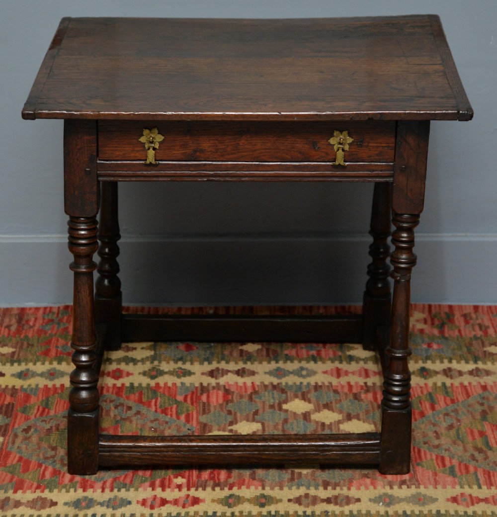 A seventeenth-century dark oak side table with turned legs, a frieze drawer with brass handles, and a low box stretcher. View VIII