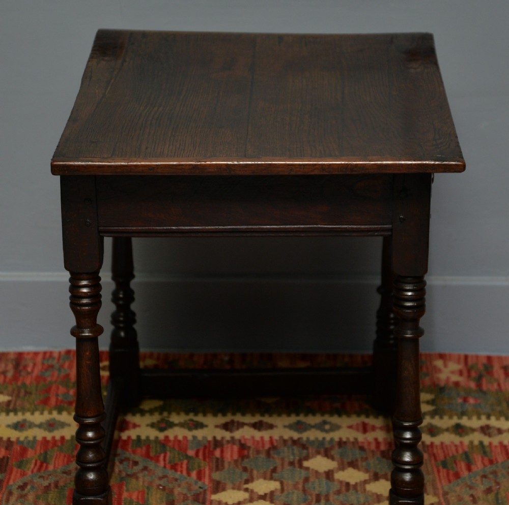 A seventeenth-century dark oak side table with turned legs, a frieze drawer with brass handles, and a low box stretcher. View IX