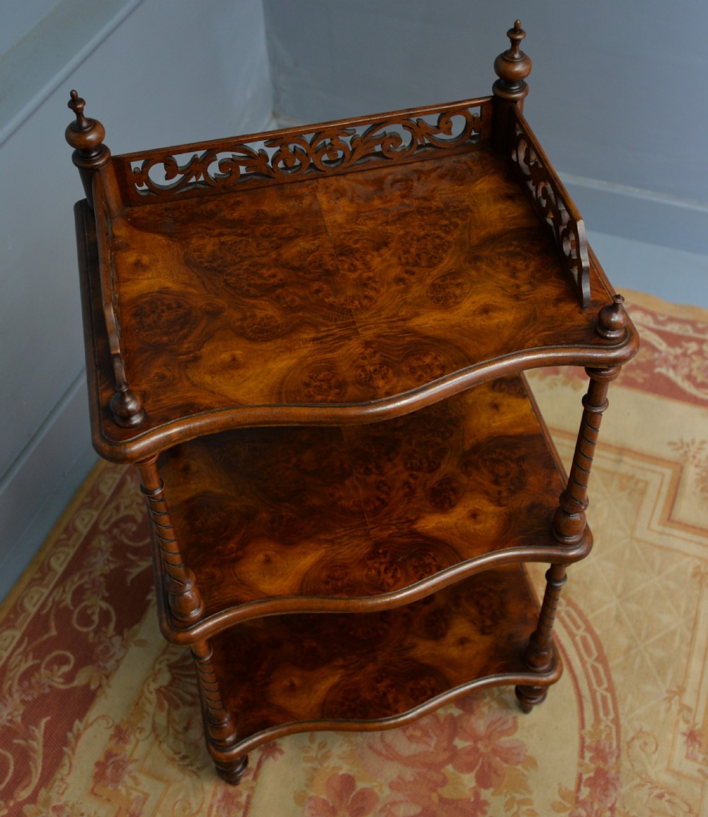 A three-tier Victorian burr walnut whatnot featuring barley twist columns, a pierced fretwork top gallery, shaped shelves, and brass castors. View XII
