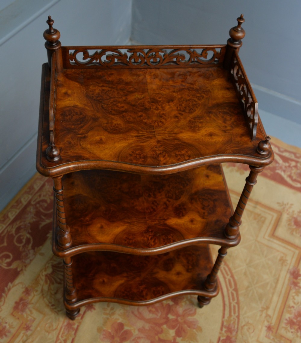 A three-tier Victorian burr walnut whatnot featuring barley twist columns, a pierced fretwork top gallery, shaped shelves, and brass castors. View XIII