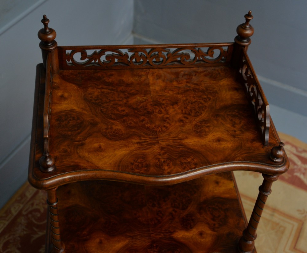 A three-tier Victorian burr walnut whatnot featuring barley twist columns, a pierced fretwork top gallery, shaped shelves, and brass castors. View XIV