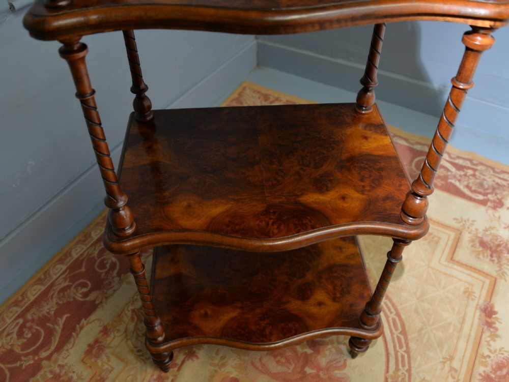 A three-tier Victorian burr walnut whatnot featuring barley twist columns, a pierced fretwork top gallery, shaped shelves, and brass castors. View XVI