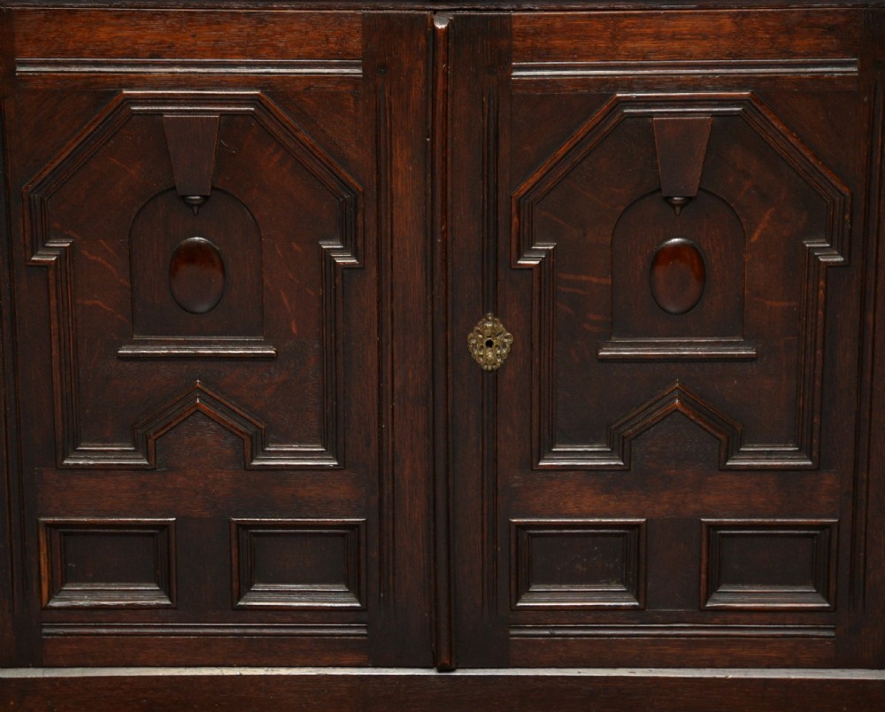 A tall dark oak Charles II chest featuring geometric moulded drawers and brass tear-drop handles above a two-door cupboard. View VI