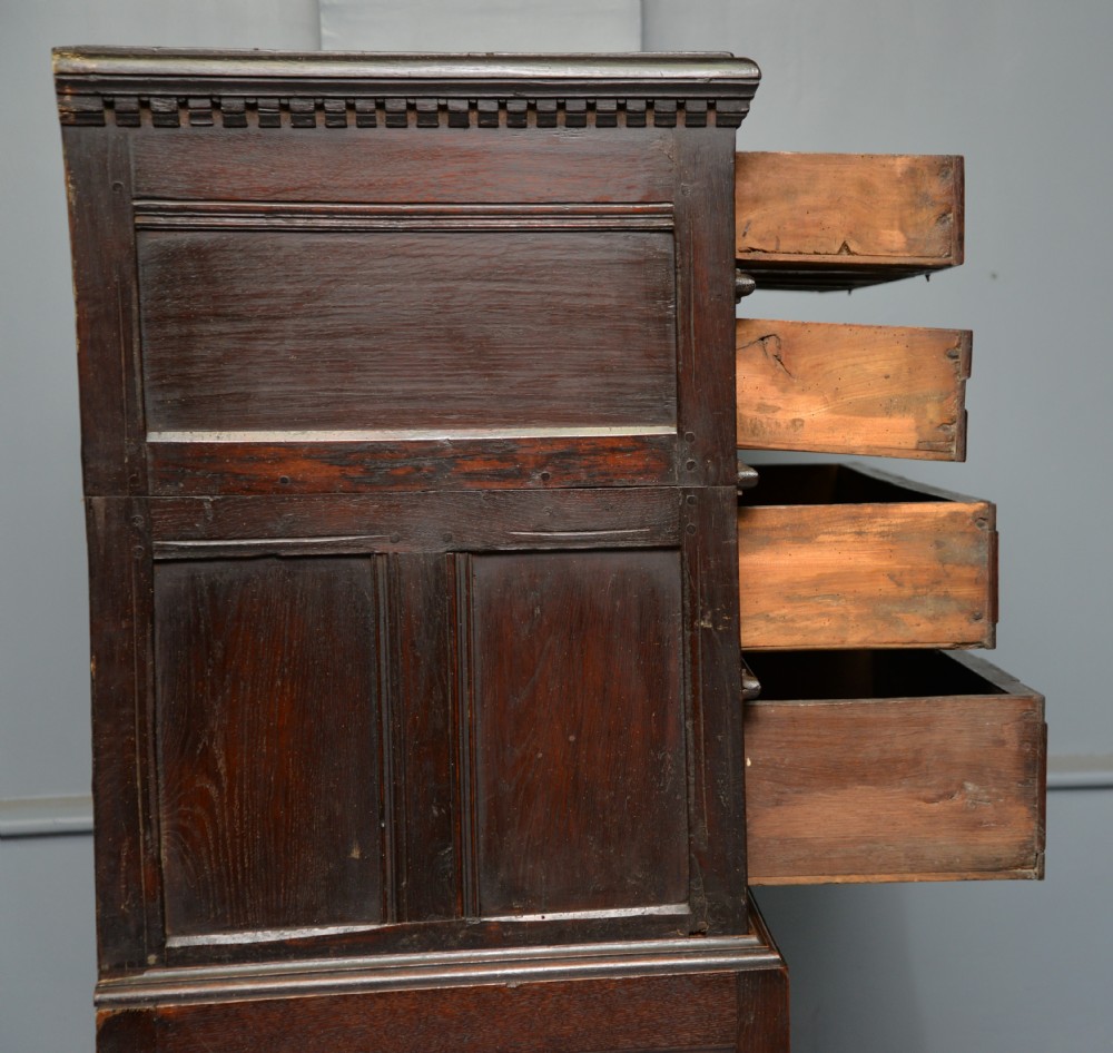 A tall dark oak Charles II chest featuring geometric moulded drawers and brass tear-drop handles above a two-door cupboard. View XIV