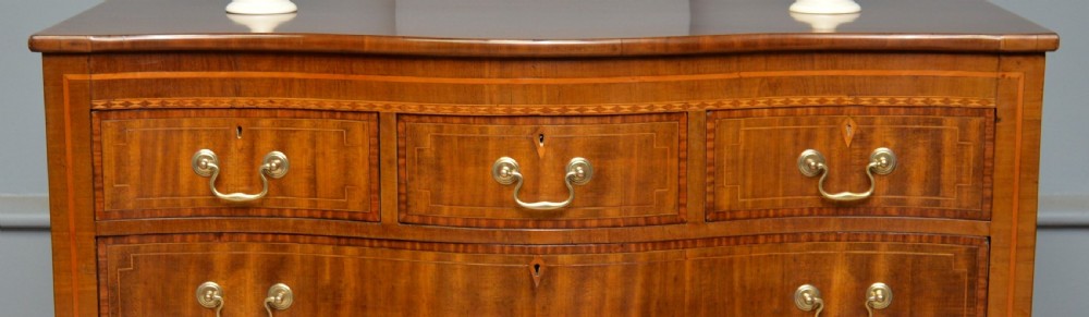 A George III mahogany chest of drawers featuring a serpentine front face, inlaid stringing borders, and brass swan-neck handles. View III