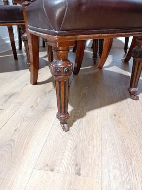 fig 1. A set of six Victorian Gothic Reform side chairs featuring dark brown leather upholstery and turned wooden front legs on brass castors.