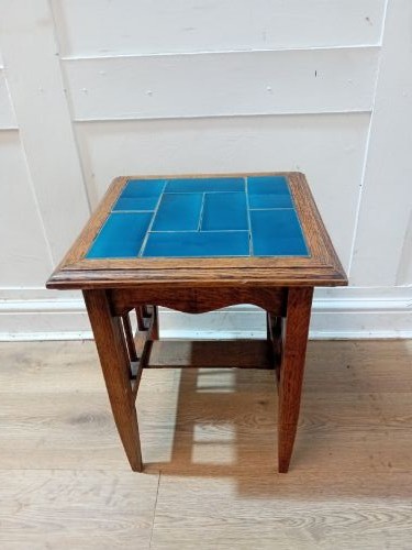 An Arts and Crafts style oak side table featuring a square top inset with vibrant blue ceramic tiles, straight tapered legs, and a lower stretcher shelf. View II