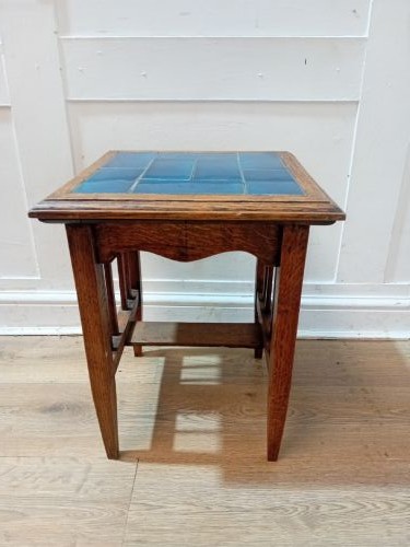 An Arts and Crafts style oak side table featuring a square top inset with vibrant blue ceramic tiles, straight tapered legs, and a lower stretcher shelf. View IV
