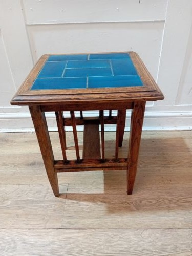 An Arts and Crafts style oak side table featuring a square top inset with vibrant blue ceramic tiles, straight tapered legs, and a lower stretcher shelf. View VI