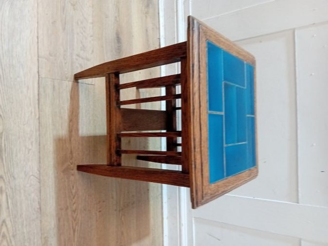 An Arts and Crafts style oak side table featuring a square top inset with vibrant blue ceramic tiles, straight tapered legs, and a lower stretcher shelf. View X