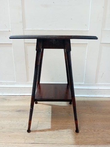 An antique dark wood Arts and Crafts side table featuring turned legs, a square top, and a lower tier shelf.